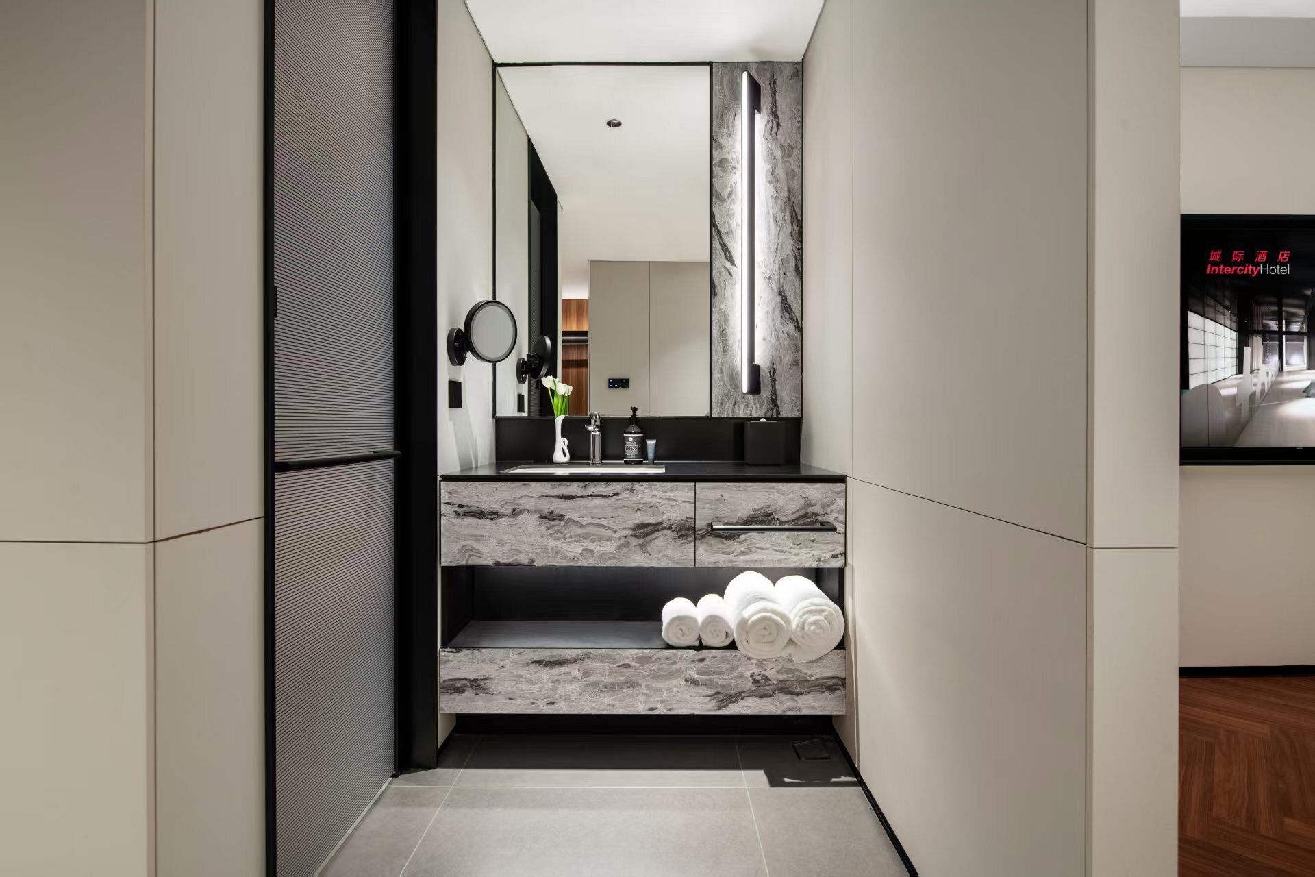 A modern bathroom with a marble countertop, a sink, a mirror, and a towel rack.