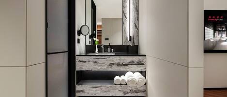 A modern bathroom with a marble countertop, a sink, a mirror, and a towel rack.