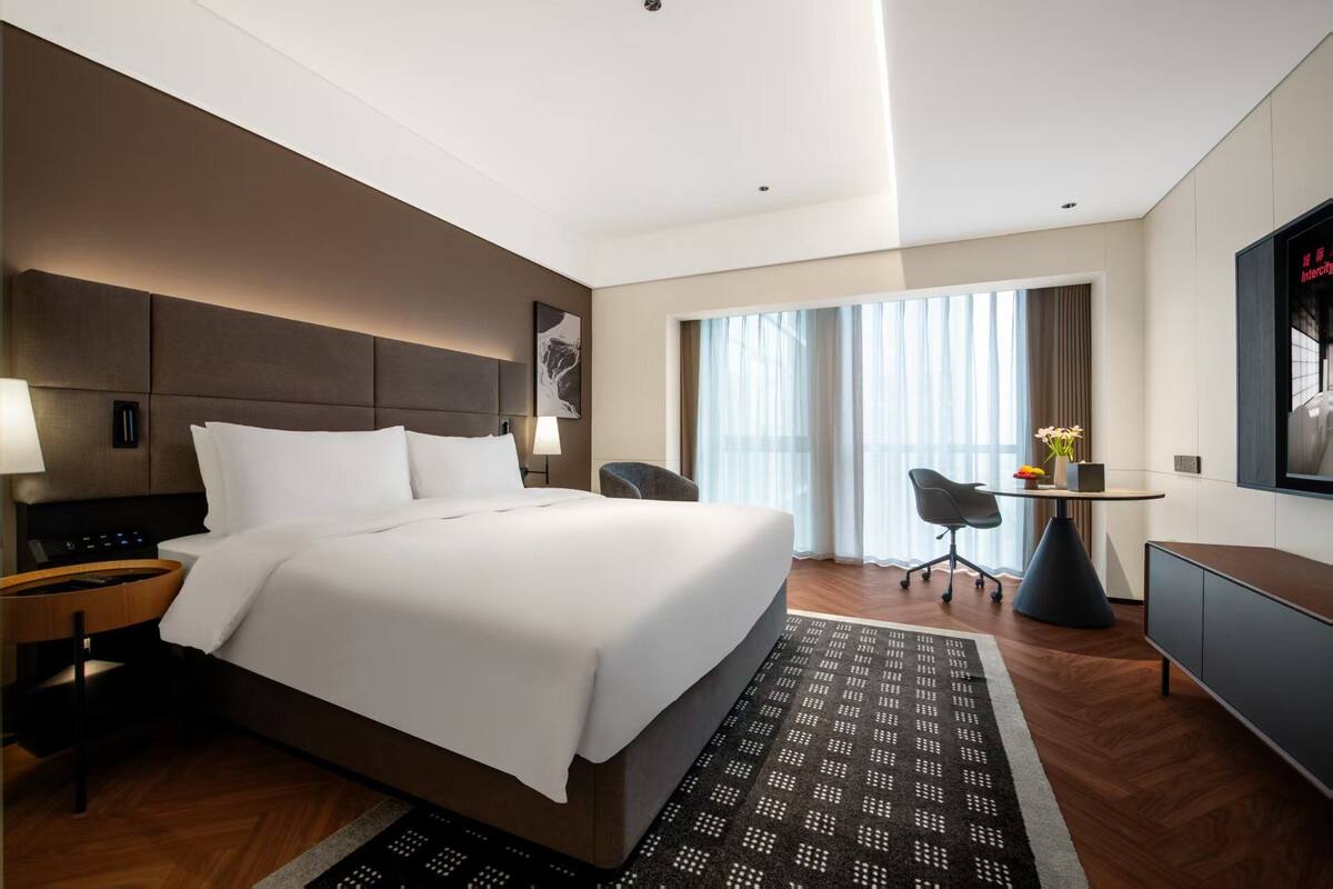 Una habitación de hotel moderna con una cama grande, un escritorio, una silla y un televisor.
