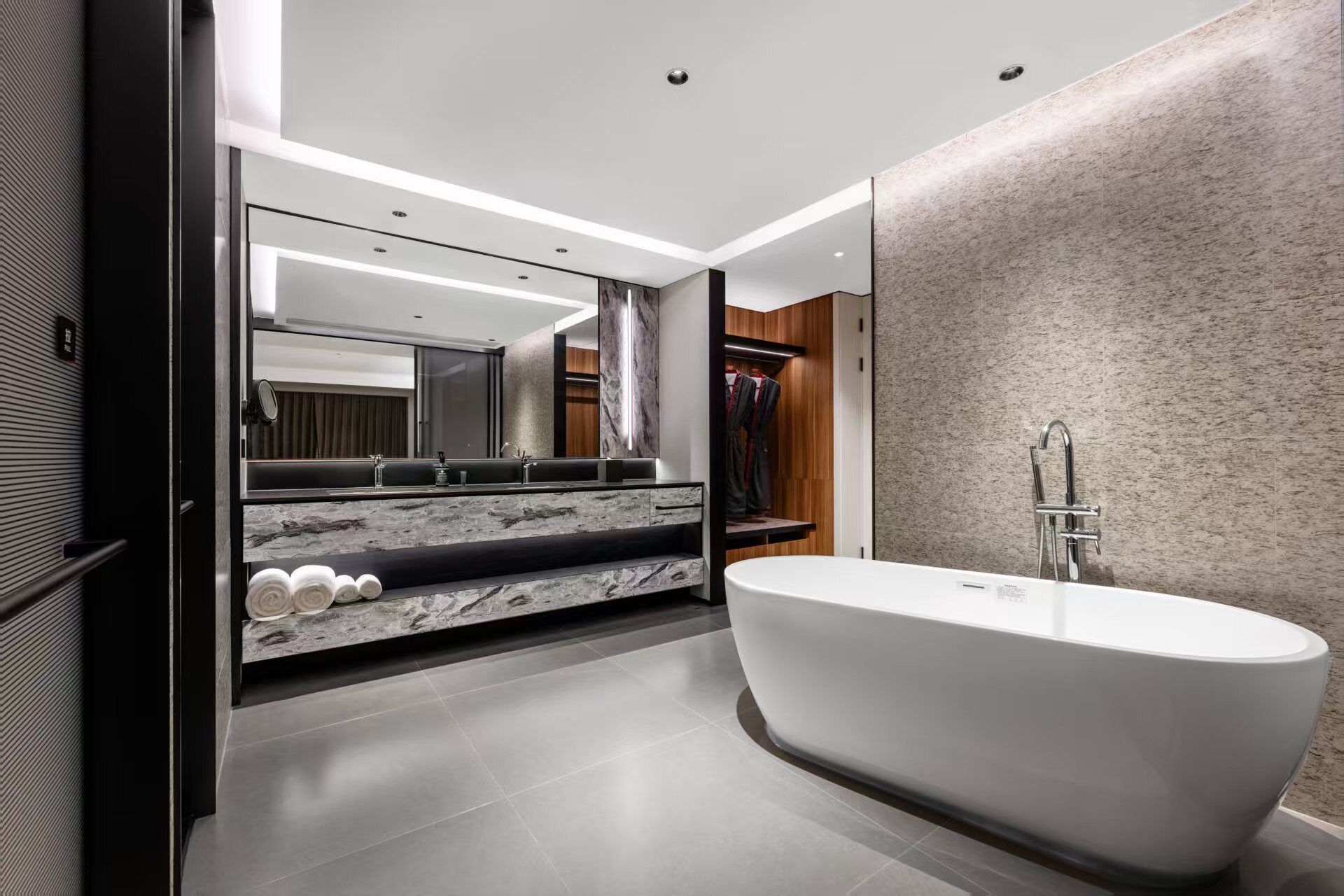A modern bathroom with a freestanding bathtub, a large mirror, and a vanity with a marble countertop.