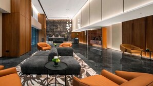 Un vestíbul modern amb una taulell de recepció, zona de seients i una catifes amb dibuixos.