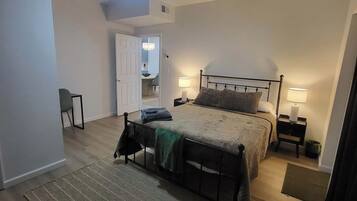 Una camera da letto con un letto, comodini, una ventola a soffitto e una porta che dà su un'altra stanza.