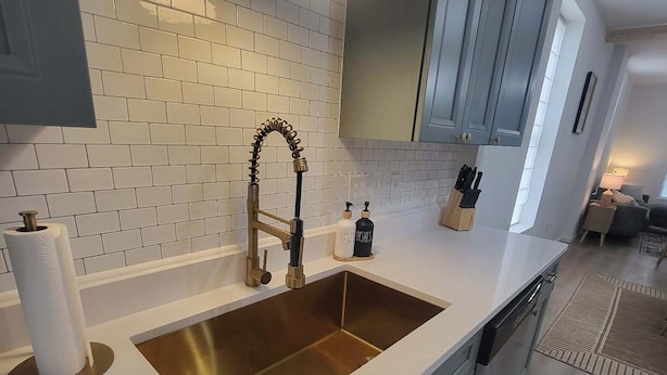 A modern kitchen with a white countertop, a stainless steel sink, and grey cabinets.
