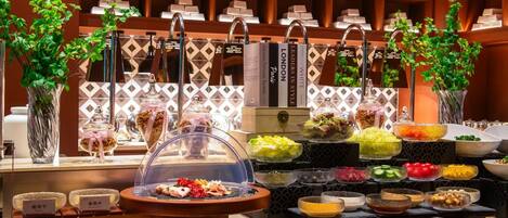 A buffet with various food items and a selection of books on shelves in the background.