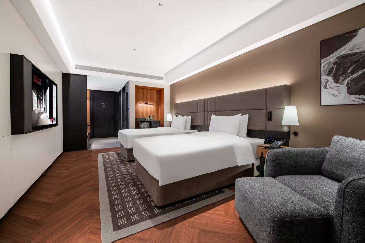 Una habitación de hotel con una cama grande, un sofá, un televisor y un escritorio con una lámpara.