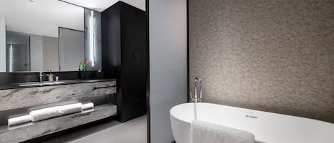 A modern bathroom with a freestanding bathtub, a large mirror, and a marble countertop.