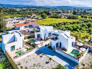 Eine moderne Villa mit Swimmingpool, mehreren Balkonen und Blick auf die umliegende Landschaft.