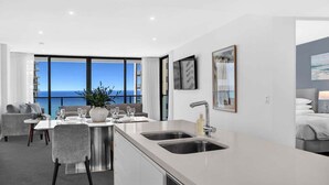 A modern kitchen with a dining area, large windows, and a view of the sea. - Sandy Beach Views at Oracle Level 25 (Gold Coast)