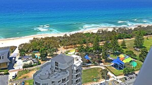 A coastal view with a beach, buildings, and a park with colorful structures. - Sandy Beach Views at Oracle Level 25 (Gold Coast)
