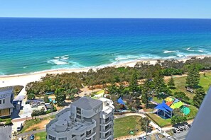 Blick auf die Küste mit Strand, Gebäuden und einem Park mit farbenfrohen Bauten.