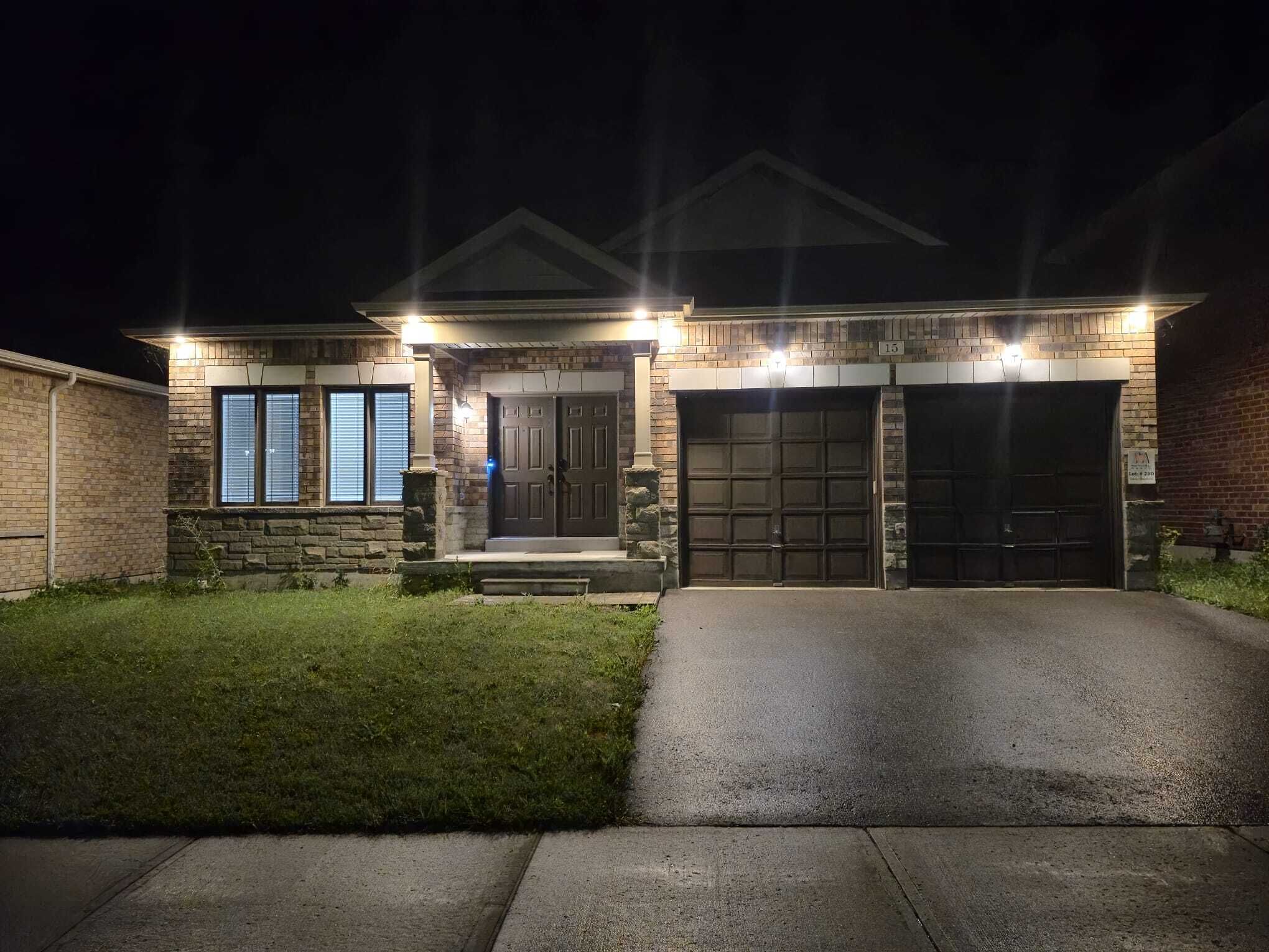 A residential house with a stone facade, two garage doors, and a well-lit front entrance.