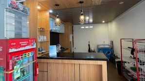 Una kitchenette con refrigerador, dos taburetes de bar, luces colgantes y techo de madera.