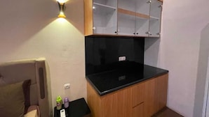 Una pequeña cocina americana con encimera negra, armarios de madera y una lámpara fijada a la pared.