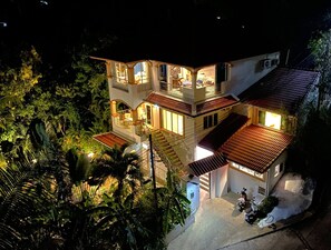 A multi-story house with balconies, a staircase, and a driveway.