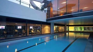 A swimming pool with lounge chairs and a glass wall. - Best Beach Views at Oracle Level 27 (Gold Coast City)