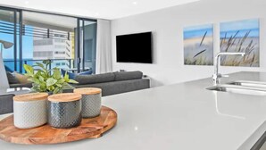 A modern kitchen with a large island, a built-in oven, a sink, and a large window overlooking a cityscape. - Best Beach Views at Oracle Level 27 (Gold Coast City)