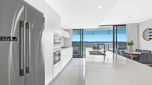 A modern kitchen with a large island, stainless steel appliances, and a view of the city. - Best Beach Views at Oracle Level 27 (Gold Coast City)