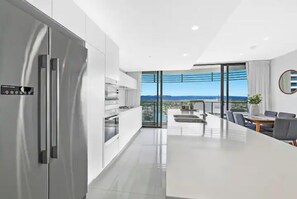 Eine moderne Küche mit einer großen Kochinsel, Edelstahlgeräten und Blick auf die Stadt.