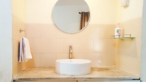 Une salle de bain avec un miroir rond, un lavabo blanc et un porte-serviettes.