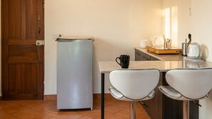 Une cuisine compacte équipée d’un réfrigérateur, d’une table avec deux chaises et d’une machine à café.