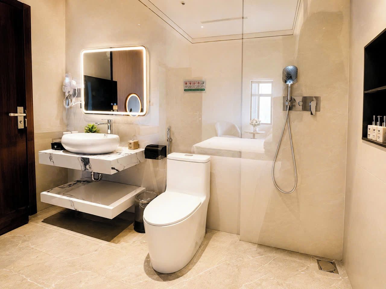 A modern bathroom with a white toilet, a sink with a marble countertop, and a shower with a handheld showerhead.