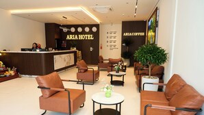 Eine Hotelhalle mit Ledersitzmöglichkeiten, einem Empfangsbereich und einer Kaffeebar.