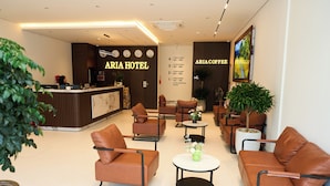 Eine Hotelhalle mit Empfangstresen, Sitzgelegenheiten und einer Kaffeestation.