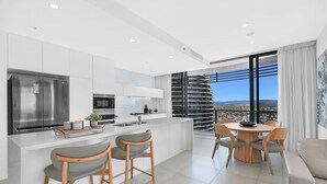 A modern kitchen with a large island, stainless steel appliances, and a dining area with a view. - Ocean and City at Oracle Level 32 (Gold Coast City)