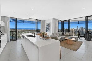 A modern apartment with a kitchen, living area, and large windows offering city views. - Ocean and City at Oracle Level 32 (Gold Coast City)