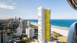 A high-rise building with a yellow facade, overlooking a beach and ocean. - Ocean and City at Oracle Level 32 (Gold Coast City)