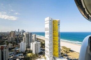 A high-rise building with a yellow facade, overlooking a beach and ocean. - Ocean and City at Oracle Level 32 (Gold Coast City)