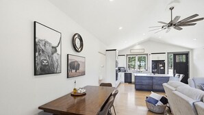 Een ruime keuken met moderne apparatuur, een eetgedeelte met een houten tafel, en een woonkamer met een bank.