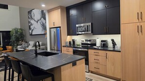 A modern kitchen with a central island, stainless steel appliances, and a mix of dark and light wood cabinetry. - Lenexa Executive Getaway (Lenexa)