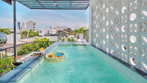 Una piscina a sfioro sul tetto con balaustra in vetro, un’area relax galleggiante e un pannello decorativo con aperture circolari.