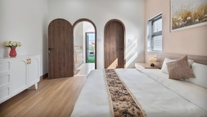 Una camera da letto con un letto, un comodino, una lampada, un quadro e vista sull'esterno.