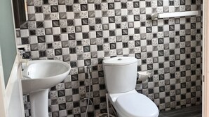 A bathroom with a checkered tile wall, a white sink, a toilet, and a shower area. - The Kumatha Residence,Second Floor Studio apartment, 5 minutes walk to the beach (Negombo)