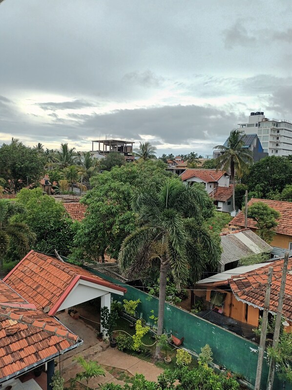 A residential area with various houses, some with red-tiled roofs, surrounded by greenery and palm trees.