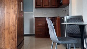 Eine moderne Küche mit Holzschränken, einem Kühlschrank, einem Esstisch mit einem Stuhl und einer Leuchte.
