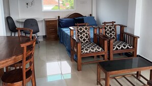 Ein Zimmer mit einem Bett, Holzstühlen, einem Tisch, einem Fernseher und einem Fenster mit Blick.