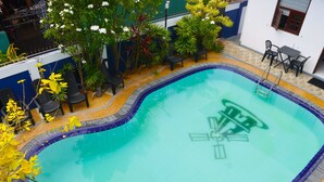 A swimming pool with a blue tiled edge, surrounded by potted plants and outdoor furniture. - The Kumatha Residence,Second Floor Studio apartment, 5 minutes walk to the beach (Negombo)