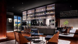 Zona de bar moderna con mostrador, asientos y una amplia exhibición de botellas.