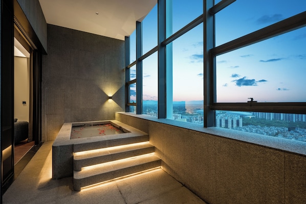 A modern interior with a stone bathtub, a view of the city through large windows, and a staircase leading to an upper level. - Intercity Hotel Chengdu Zhonghe (Chengdu)