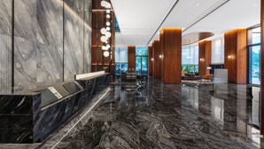 A modern lobby with a marble reception desk, wooden accents, and a view of greenery outside. - Intercity Hotel Chengdu Zhonghe (Chengdu)
