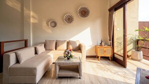 A living room with a sofa, a coffee table, and decorative wall art. - Villa Ciconia Ubud (Ubud)