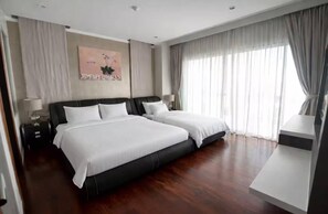 A hotel room with two beds, a desk, a lamp, a painting, and a large window with curtains. - Chalong Miracle Lakeview 4021 (Chalong)