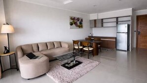 Uma sala de estar moderna com um sofá, uma mesa de centro e uma área de jantar com cadeiras.