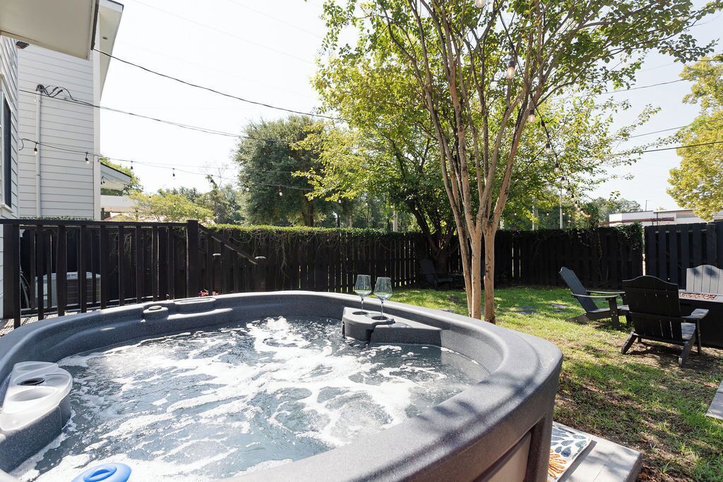 Ein Whirlpool in einem Garten mit Holzzaun, Baum und Gartenmöbeln.