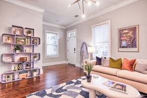 Ein Wohnzimmer mit einem beigefarbenen Sofa, einem Couchtisch und einem Bücherregal mit Dekoration.