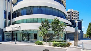 Un edificio moderno con fachada curva, entrada de vidrio y un letrero que dice 'PEPPERS'.