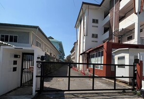 Ein verschlossenes Tor führt zu einem Mehrfamilienhaus mit mehreren Etagen und Balkonen.